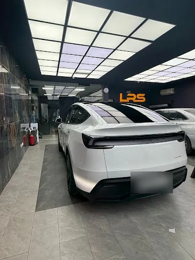 سيارة بيضاء من الخلف أمام شعار LRS